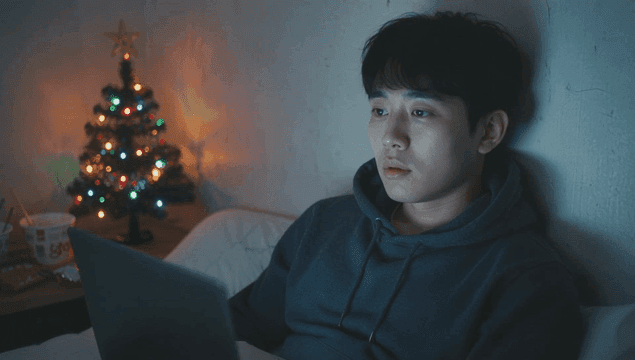 크리스마스 트리가 있는 어두운 방에서 노트북을 사용하는 젊은 남성