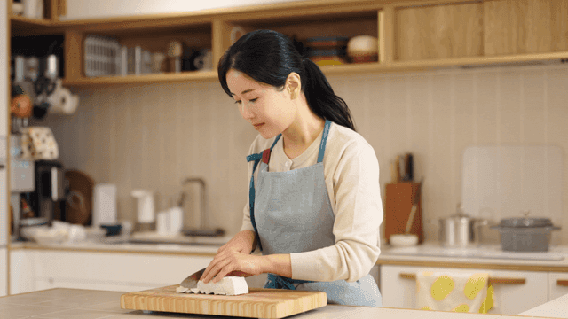 Woman cutting tofu in kitchen