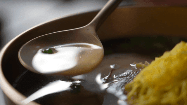 Spoon that scoops up clear broth topped with egg