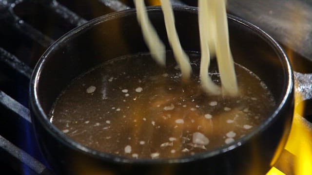 Udon noodles boiling in a pot on a stove