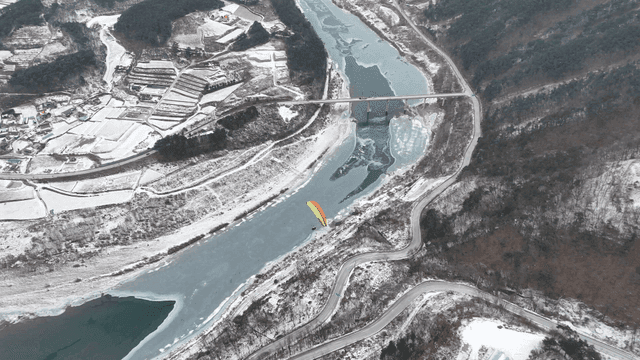 Paragliders over snow-covered landscape and frozen river