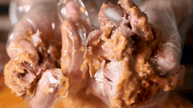 Pork backbones for Gamjatang, torn apart with gloved hands