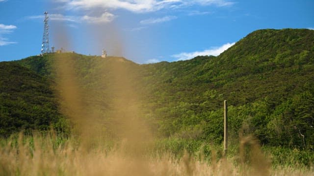 Telecommunication Tower on a Green Hill Under a Clear Sky