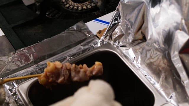 주방에서 꼬치구이에 소스를 바르는 장갑 낀 손