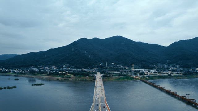 산이 보이는 넓은 강을 가로지르는 다리