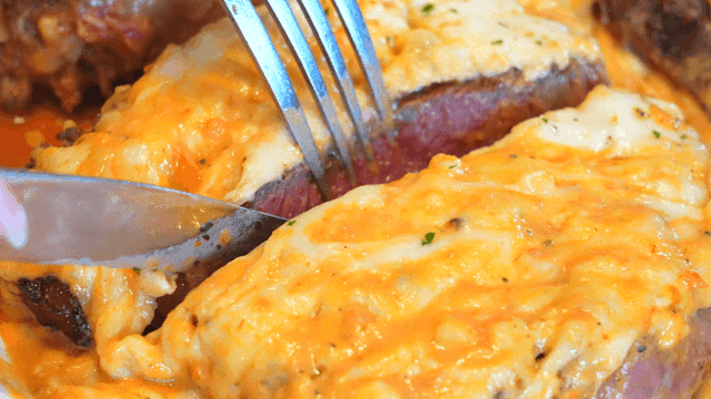 Cheesy steak being sliced with a knife