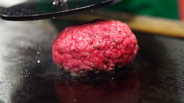 Hamburger beef patty being pressed on a grill