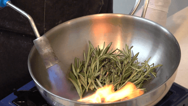 Roasting rosemary in pan by torch