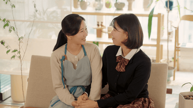 Mother and daughter smiling and holding hands at home