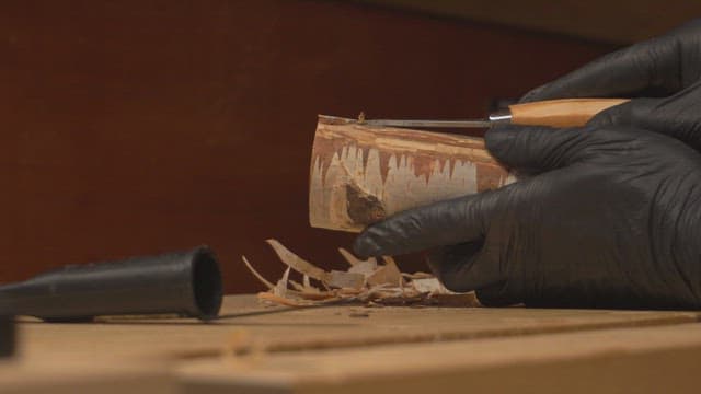 Hands carving wood with a chisel