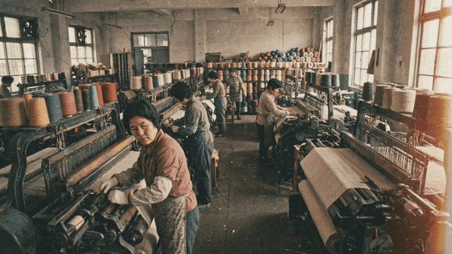 Workers operating textile machines in a factory