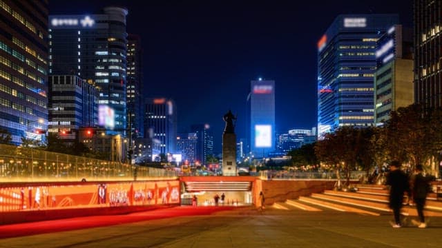 Busy city night view of statues and illuminated buildings