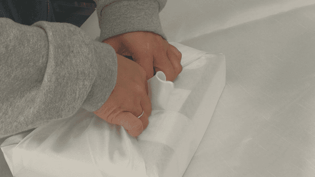 Hand wrapping gift in white traditional cloth