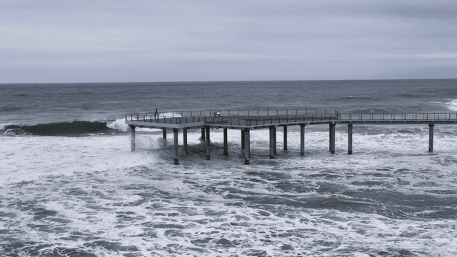 Pier extending into wave-crashing sea