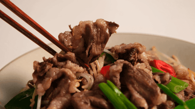 Chopsticks holding stir-fried beef with vegetables