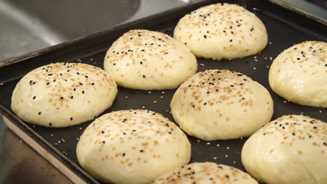 Burger bun dough sprinkled with sesame seeds