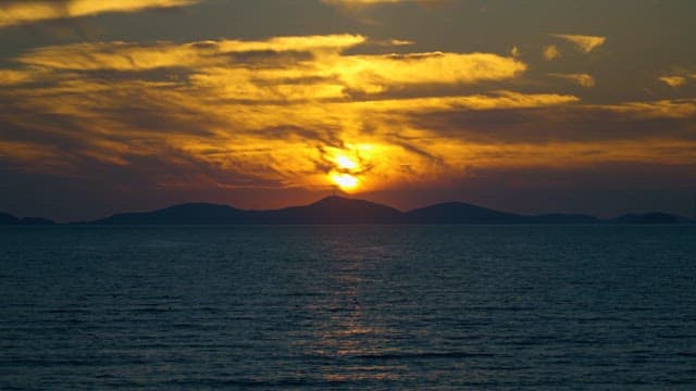 Sunset View Over Sea and Silhouetted Mountains