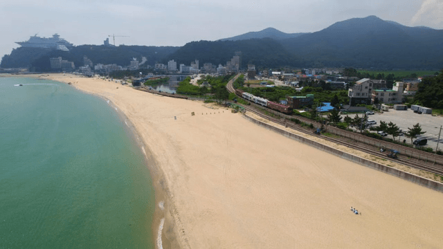 세 사람이 앉아서 손을 흔드는 모래사장의 전경