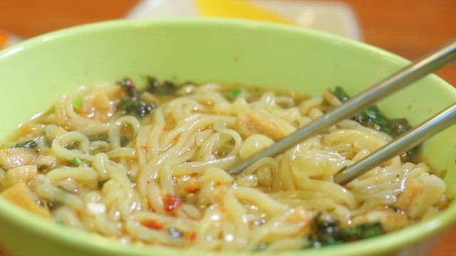 A bowl of steaming noodles with chopsticks