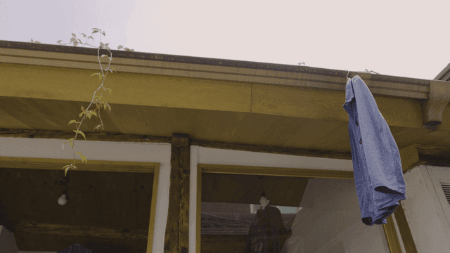 Blue shirt hanging from eaves of house