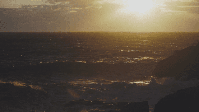 Sunset over the ocean with waves crashing