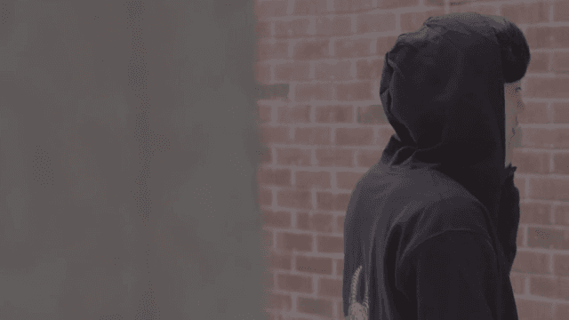 골목길에 서서 전화를 하는 후드티 입은 남자