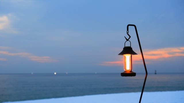 Lantern glowing at dusk by the peaceful sea