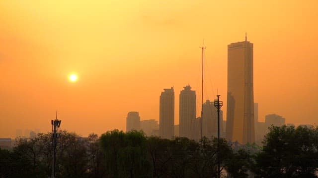 City skyline at sunset with orange sky and trees