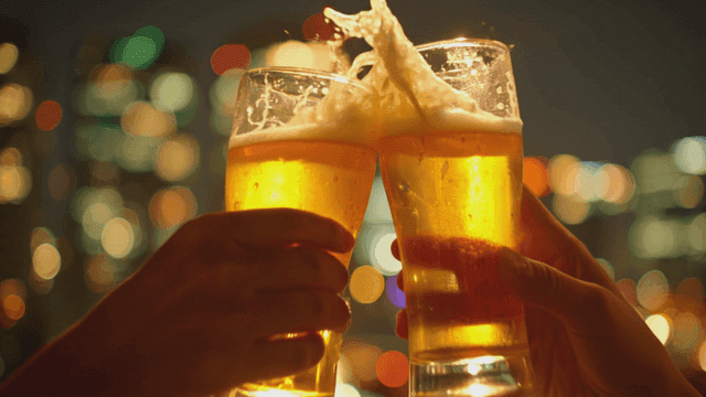 야경 불빛을 배경으로 맥주잔을 부딪히는 두 사람