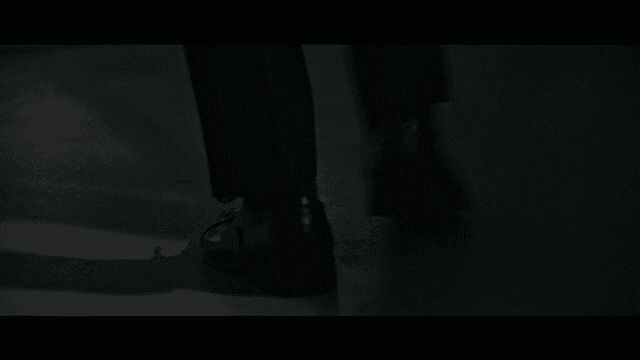 Person walking on dark floor wearing shoes