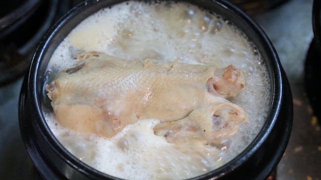 Chicken boiling in a pot of ginseng chicken soup