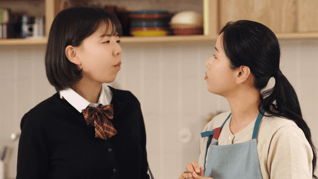 Mother and daughter enjoying meal together in kitchen