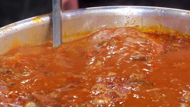 Pork backbone stew meat transferred from a large pot to a small pot