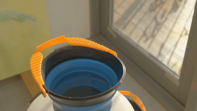 창가에 있는 주황색 손잡이의 파란 물통