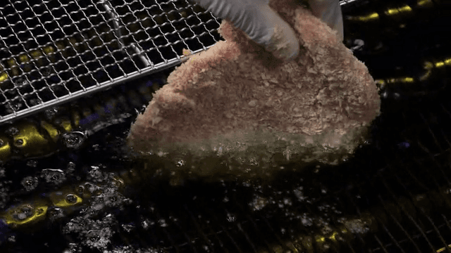 Breaded raw pork being fried in hot oil
