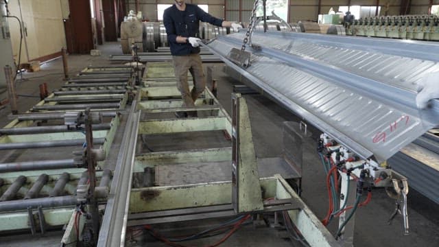 Worker handling metal sheets in a factory