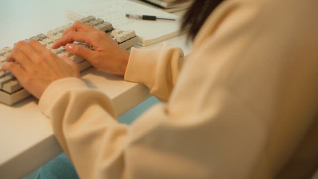 Woman using a keyboard at a desk in a calmly lit room