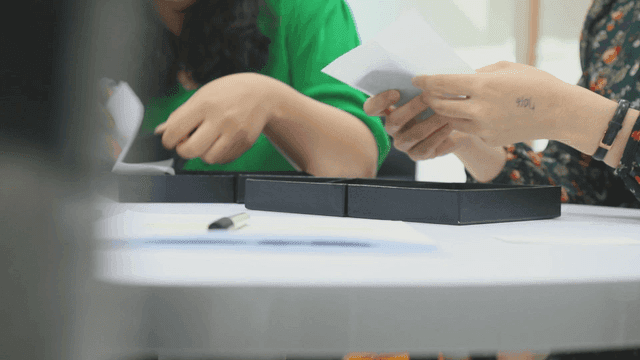 검은 상자를 열어 제품을 확인하는 사람들