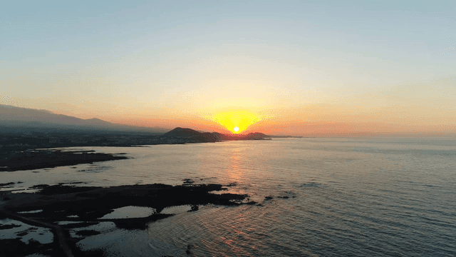 Sunset over the ocean with distant mountains