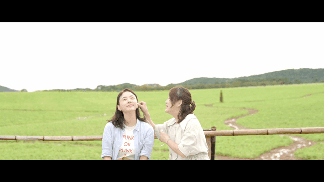 Two women sharing earphones in meadow