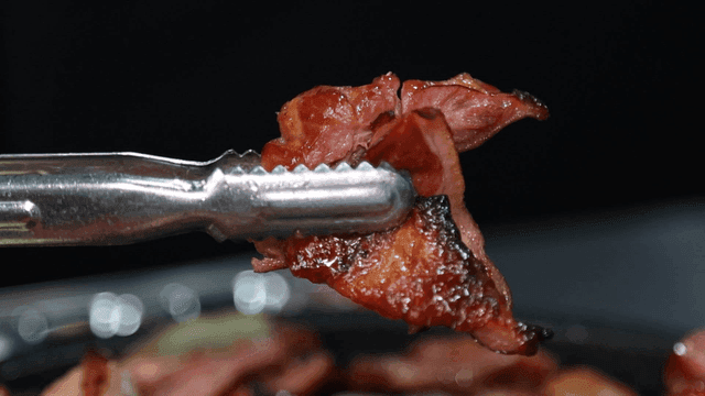 Grilled meat picked up with tongs