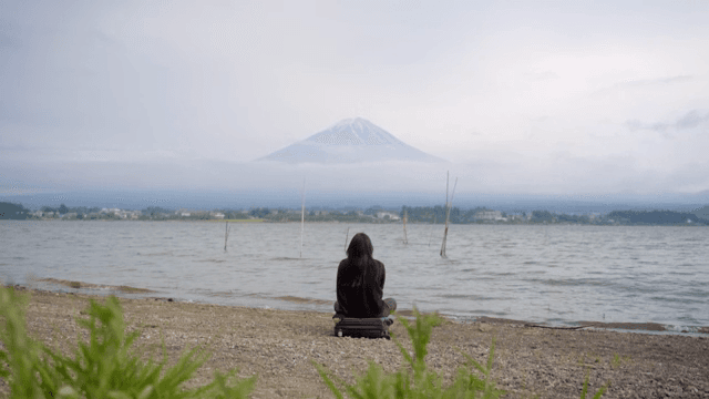 후지산이 보이는 호숫가에 앉아 있는 사람