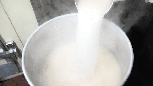 Pouring steaming white broth from pot