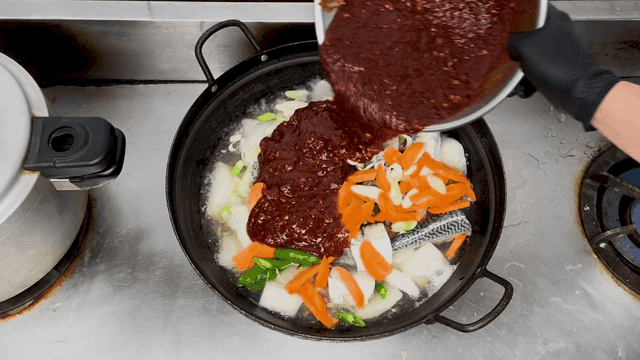 끓는 냄비에 매운 소스가 추가된 고등어무조림