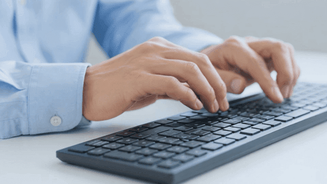 Hands typing on a keyboard in an office
