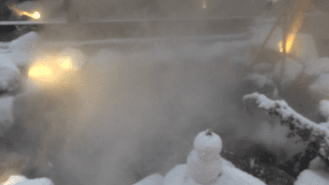 Snow-covered hot spring with steam rising