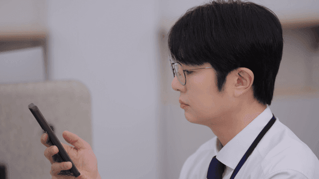 사무실 책상에서 스마트폰을 사용하는 남성