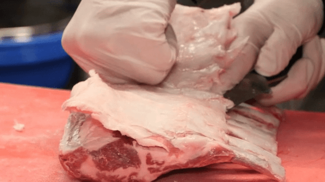 Trimming fat from a rack of lamb