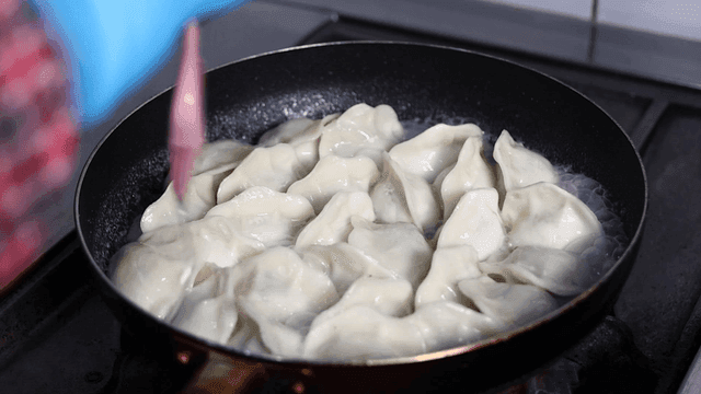 Oil poured over dumplings boiling in pan