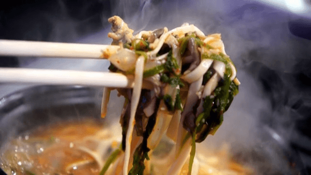 버섯 칼국수를 젓가락으로 들어올리는 모습